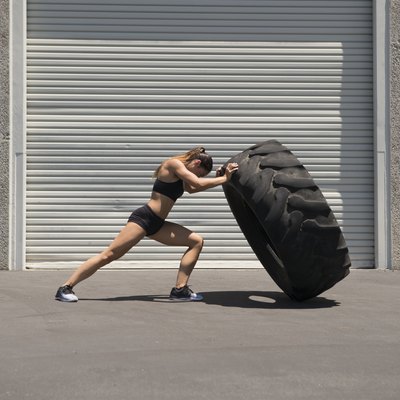 Young woman lifting a giant tire
