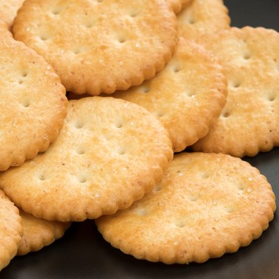 crackers cheese and crackers sugar in black plate on wood table