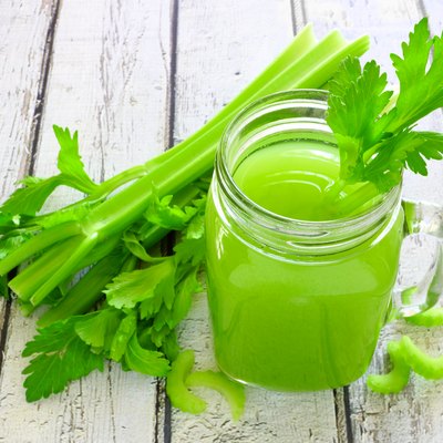 Celery juice in a mason jar against a white wood background