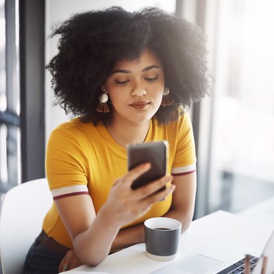 Woman reading nutrition or weight-loss articles on smartphone with laptop
