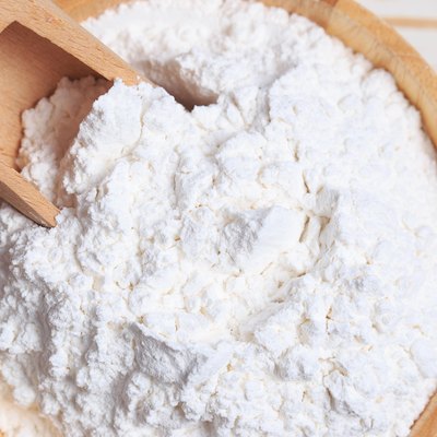 Close-Up Of Flour With Serving Scoop In Wooden Bowl On Table
