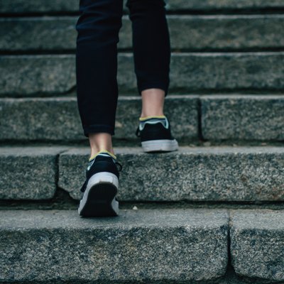 The girl in black jeans climbs on concrete stairs