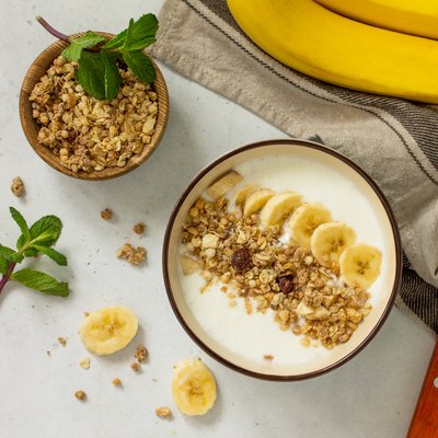 Granola. Granola with yogurt, chocolate and banana on a white stone table.