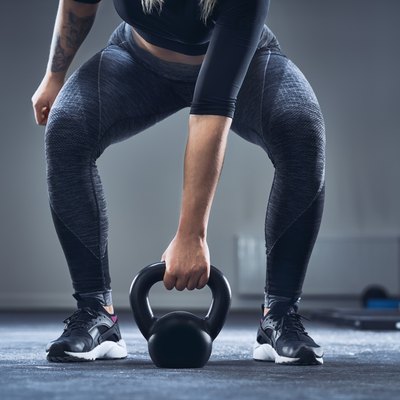 Close-up of athletic woman exercising with kettlebell at gym