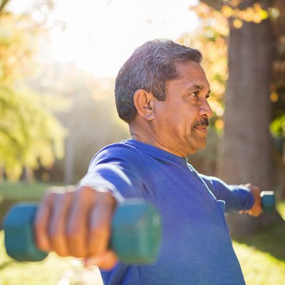 Man exercising with dumbbell on sunny day