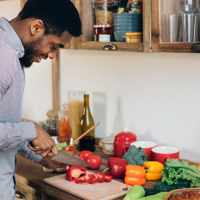 An African-American man cutting a bell pepper in his kitchen