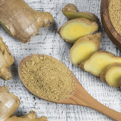 Fresh chopped ginger root and ground ginger powder in wooden spoon on wooden rustic table. Healthy food spice concept. Zingiber officinale