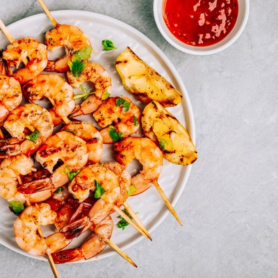 Sweet Chilli Shrimp Skewers with lemon and parsley on gray stone background