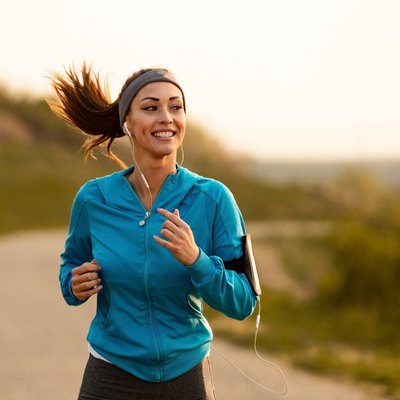 Happy female runner jogging in the morning in nature.