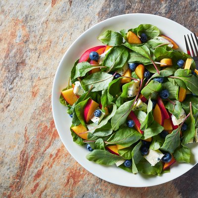 healthy salad with fresh chard leaves, peach, blueberries, pieces of cheese