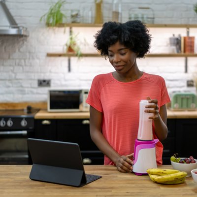 Woman making a smoothie at home following an online recipe