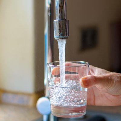 Cropped Hand Filling Glass With Water From Faucet