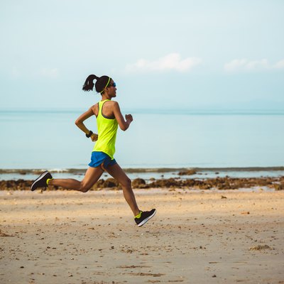 Young fitness woman running on beach