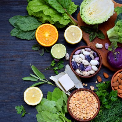 Composition on a dark background of products containing folic acid, vitamin B9 - green leafy vegetables, citrus, beans, peas, nuts, yeast. Top view. Flat lay