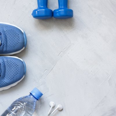 Flat lay sport shoes, bottle of water, dumbbells and earphones