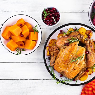 Roasted turkey garnished with cranberries on a rustic style table decorated autumn leaf. Thanksgiving Day. Baked chicken. Top view
