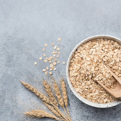 Rolled oats, oat flakes in bowl on concrete background
