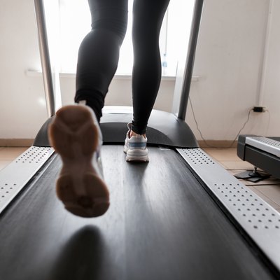 Women's legs run on a treadmill. Young woman engaged in fitness in the gym. Girl in training in the gym. Back view.