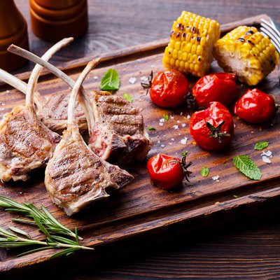 venison ribs grilled on cutting board with roasted vegetables.