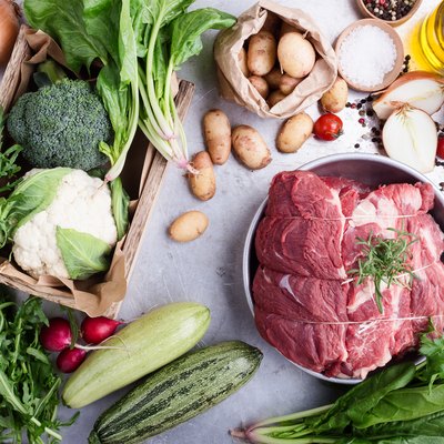 Cut of steak and variety of green vegetables and herbs