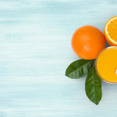 Orange juice glass and fruits on blue wooden tropical background