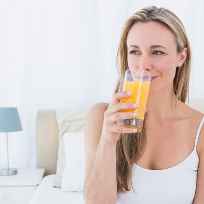 Woman drinking glass of vitamin C orange juice before going to sleep