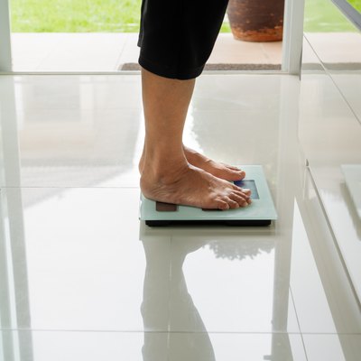 old woman standing on weight scale in living room