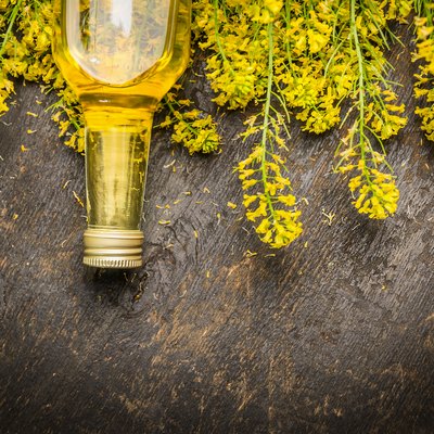 Oil and plant blossoms on dark rustic wooden background