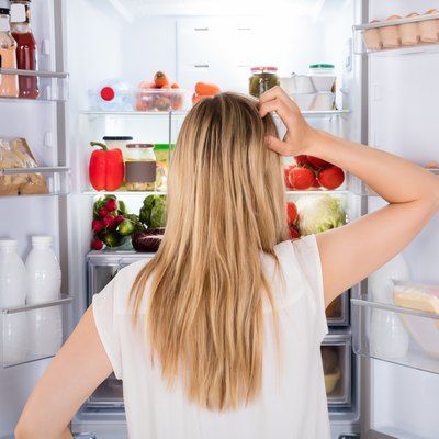 Rear view of a hungry woman looking in the fridge for something to eat