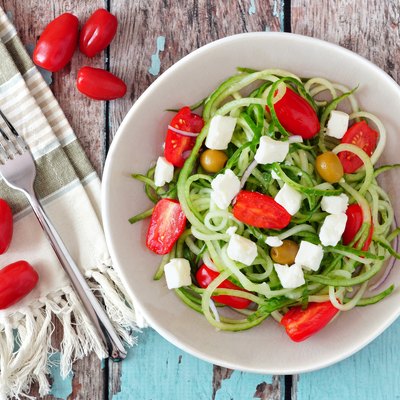 Greek Salad with cucumber noodles, overhead scene on rustic wood