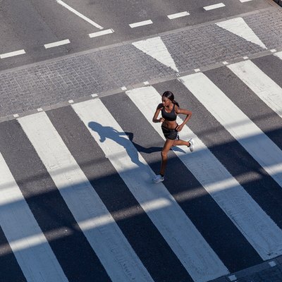 Young woman running on zebra crossing