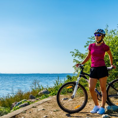 Woman cycling for exercise on trail near ocean