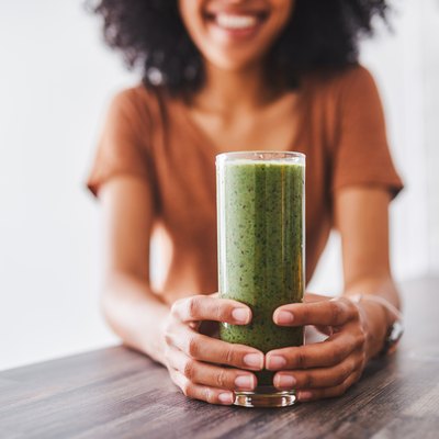 Woman holding green drink.