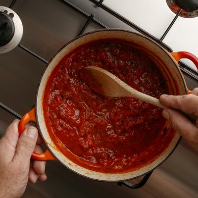 Cooking a traditional gormet tomato sauce and wooden spoon, on a stainless steal hob