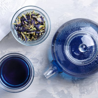 Butterfly pea flower tea is brewed in a glass teapot and served into a transparent cup. Blue herbal tea. Top view.