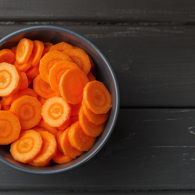 Sliced carrots in a bowl on black background