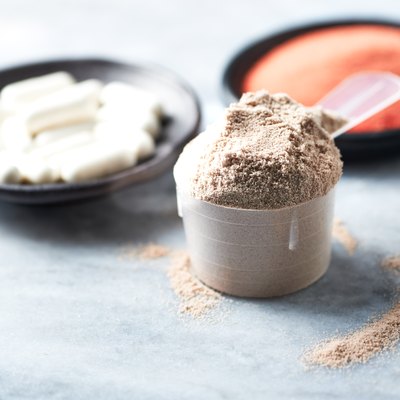 Scoop of Whey Protein, Beta-alanine capsules and Creatine Powder. Sport nutrition. Stone background. Copy space