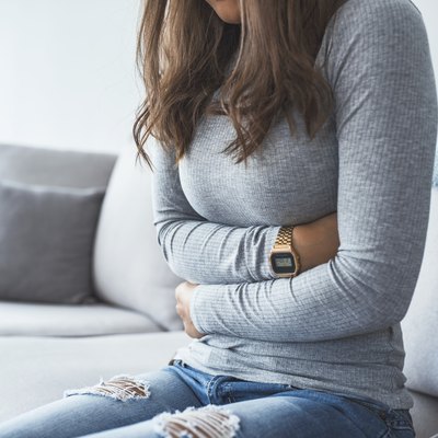 Woman sitting on the sofa feeling full and bloated after eating