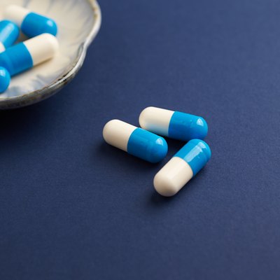 Tri-Creatine Malate capsules. Bodybuilding food supplements on blue paper background. Close up. Copy space.