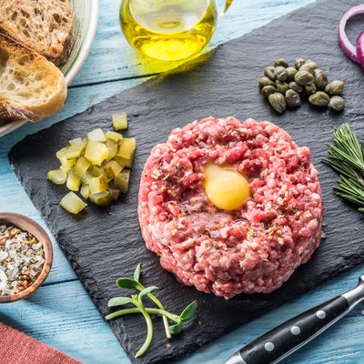 Steak tartare served with raw quail egg yolk, capers and bread. Meat dish.