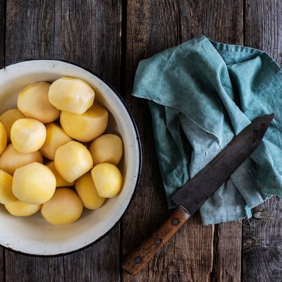 Directly Above Shot Of Peeled Boiled Potatoes In Bowl By Napkin And Knife On Table