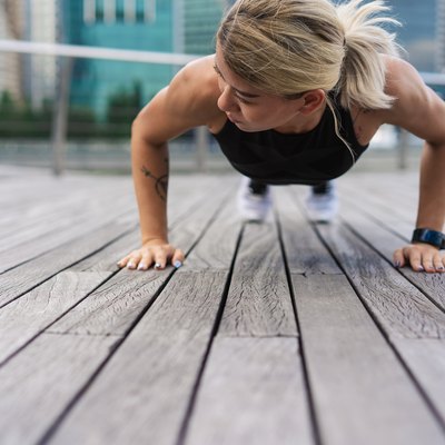 Exercise woman doing push ups in outdoor workout training.