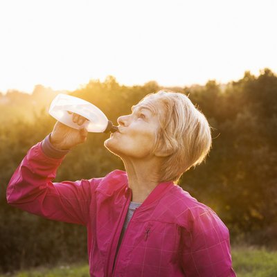 Senior woman drinking water after run outdoors