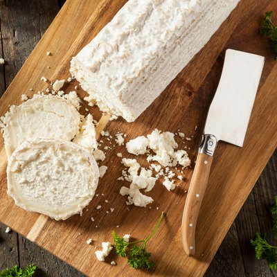 Raw white organic goat cheese on a cutting board.