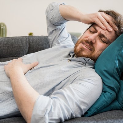 Guy feeling unwell with a stomach ache while sitting at home