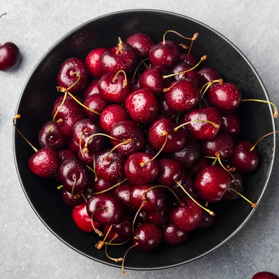 Fresh ripe black cherries in a black bowl, top view