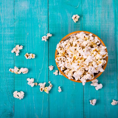 corn popcorn on a blue wooden background, as a snack for watching movies