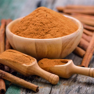 Close-Up Of Cinnamons With Grounded Spice On Table