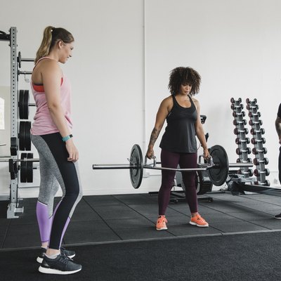 Women Deadlifting Weights with a Personal Trainer in the Gym