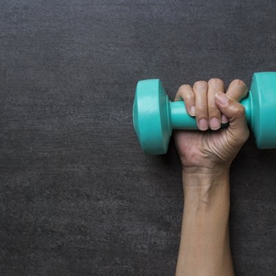 woman hand holding green dumbbell on black background